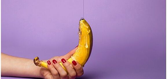 mano di donna che tiene una banana ricoperta di lubrificante