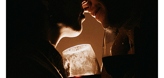 due uomini che si baciano con due calici di vino