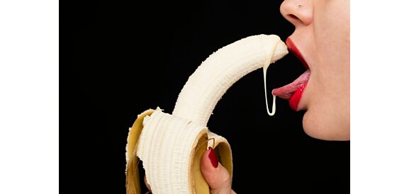 Woman licking liquid off of a banana